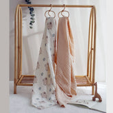 Fluffy Sheep swaddle and cream muslin blanket hanging side by side on nursery rail